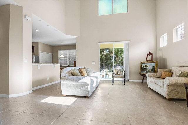 living room featuring light tile patterned flooring, a towering ceiling, and baseboards