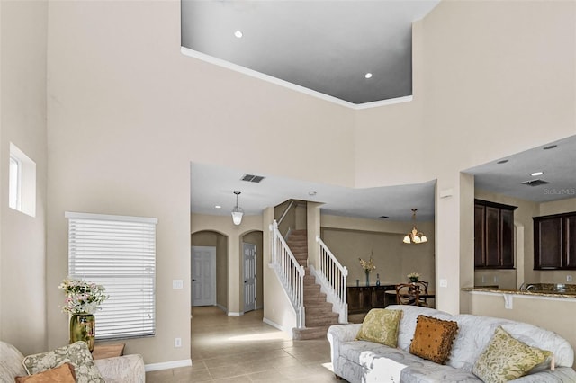 living area featuring arched walkways, a high ceiling, visible vents, baseboards, and stairs