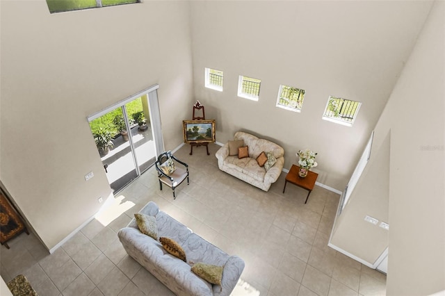 tiled living room with a high ceiling and baseboards