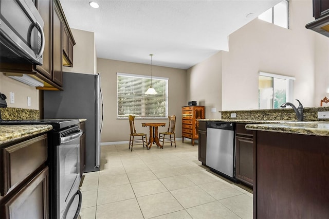 kitchen featuring light stone counters, light tile patterned floors, hanging light fixtures, appliances with stainless steel finishes, and dark brown cabinetry