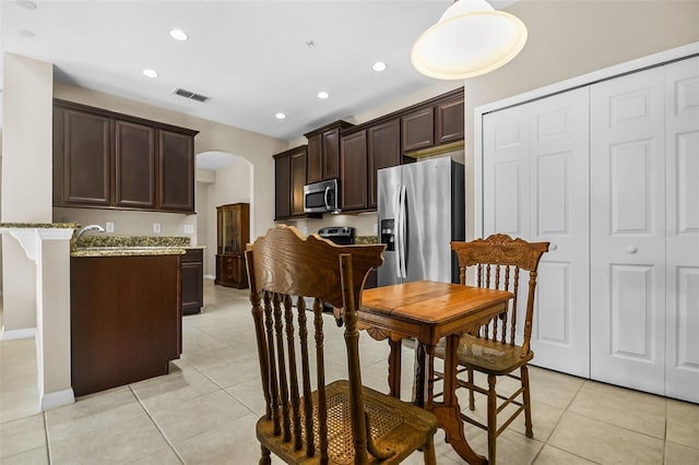 kitchen with light tile patterned floors, visible vents, arched walkways, appliances with stainless steel finishes, and dark brown cabinets