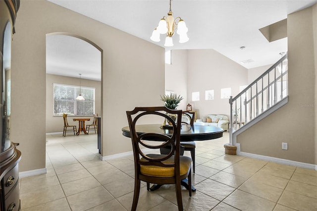 dining space with lofted ceiling, light tile patterned floors, baseboards, and arched walkways