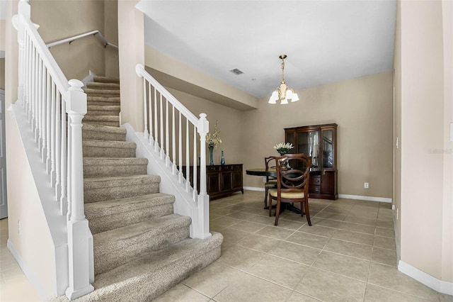 stairway featuring baseboards, tile patterned flooring, visible vents, and an inviting chandelier