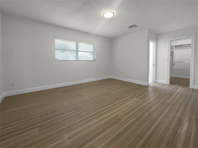 unfurnished bedroom with baseboards, visible vents, wood finished floors, a textured ceiling, and a closet