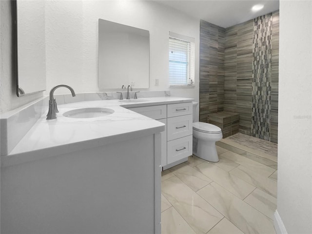 full bathroom featuring a tile shower, vanity, and toilet