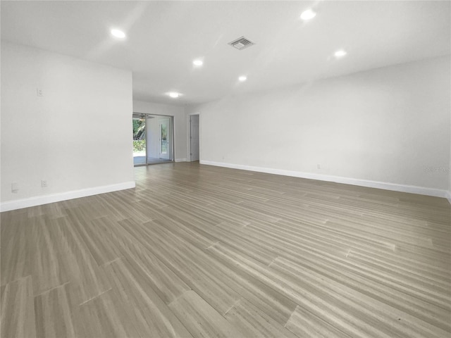 empty room with light wood-style floors, baseboards, visible vents, and recessed lighting