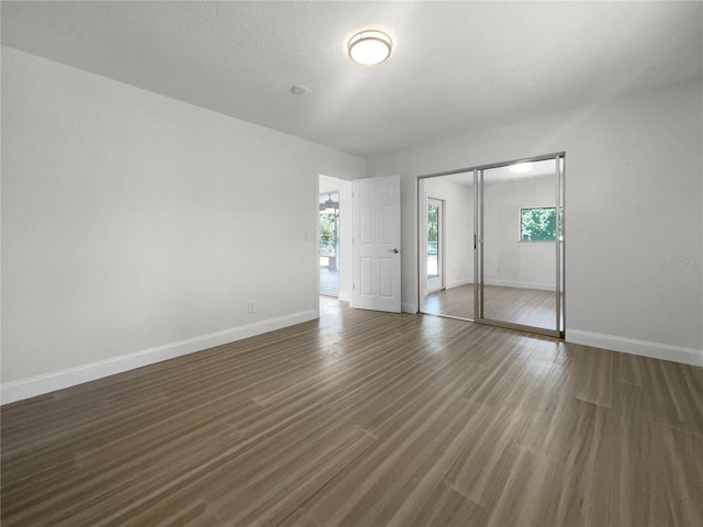 unfurnished bedroom with a closet, baseboards, and wood finished floors