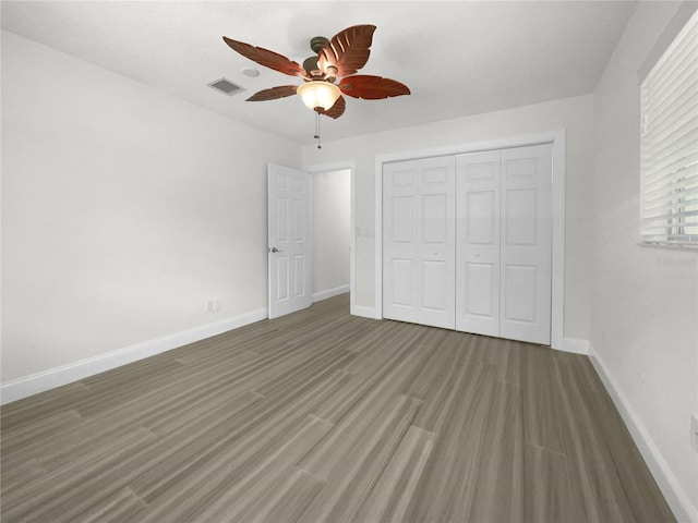 unfurnished bedroom featuring wood finished floors, a ceiling fan, visible vents, baseboards, and a closet