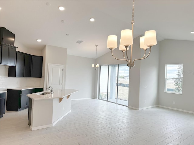 kitchen with a center island with sink, a healthy amount of sunlight, sink, and a chandelier