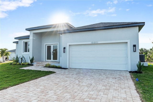 view of front of property with a garage, central AC, and a front lawn