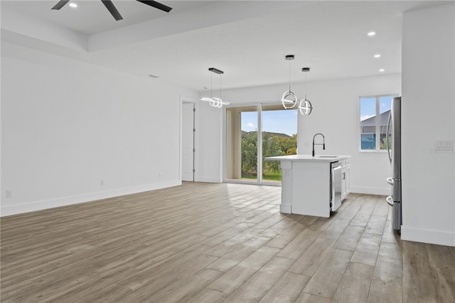 kitchen featuring decorative light fixtures, a kitchen island with sink, ceiling fan, light hardwood / wood-style floors, and stainless steel appliances