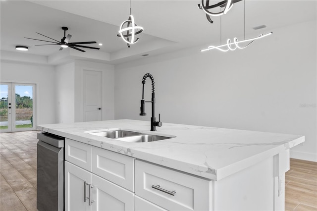 kitchen featuring sink, decorative light fixtures, a tray ceiling, light stone countertops, and white cabinets