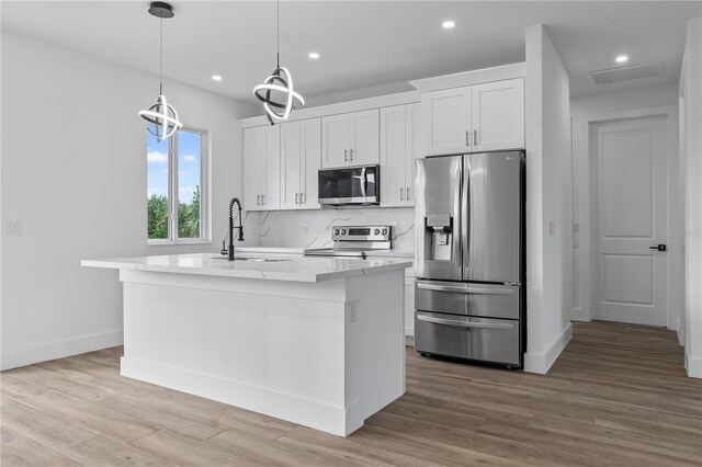 kitchen featuring stainless steel appliances, sink, an island with sink, and white cabinets