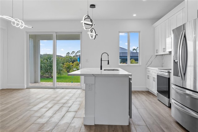 kitchen with sink, white cabinetry, a kitchen island with sink, stainless steel appliances, and decorative light fixtures