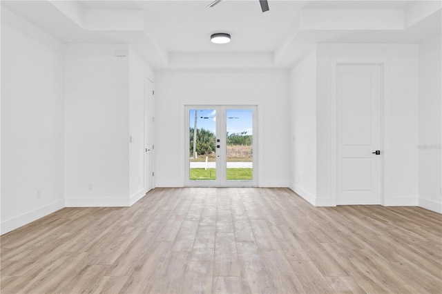 spare room featuring a raised ceiling, french doors, ceiling fan, and light hardwood / wood-style flooring