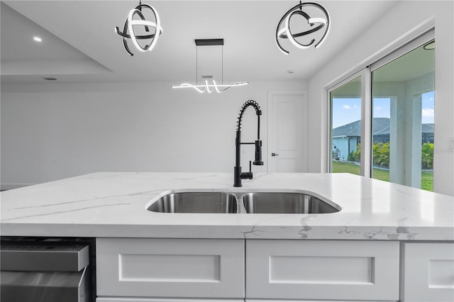 kitchen with white cabinetry, sink, light stone counters, and pendant lighting