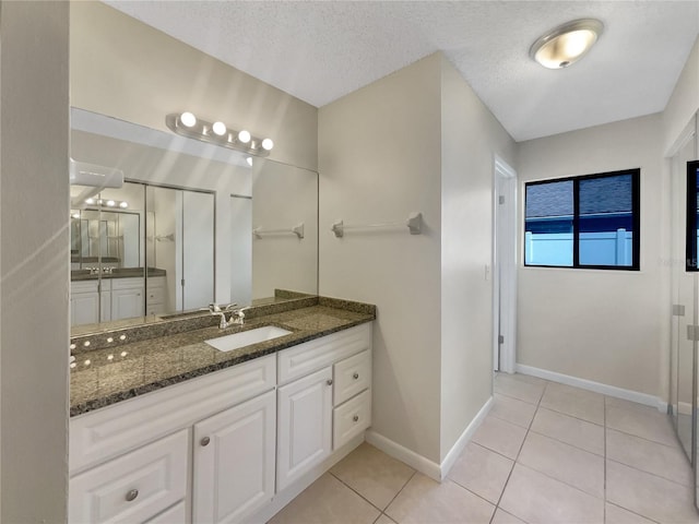 full bath featuring baseboards, vanity, a stall shower, tile patterned floors, and a textured ceiling