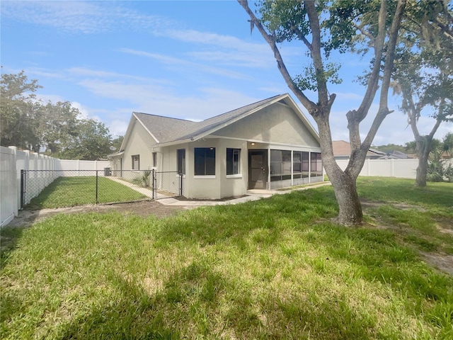 rear view of house featuring stucco siding, a gate, a fenced backyard, a yard, and a sunroom