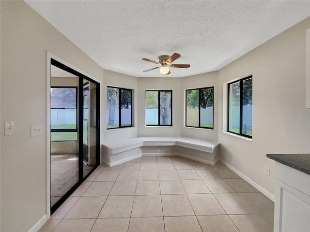 spare room featuring ceiling fan, light tile patterned floors, baseboards, and a textured ceiling