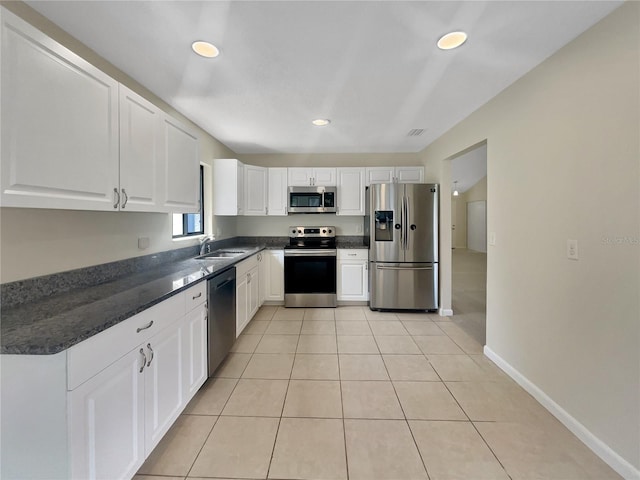 kitchen with light tile patterned floors, appliances with stainless steel finishes, white cabinetry, and a sink