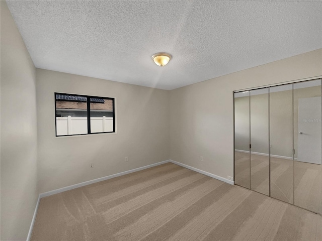 unfurnished bedroom with carpet floors, baseboards, a closet, and a textured ceiling