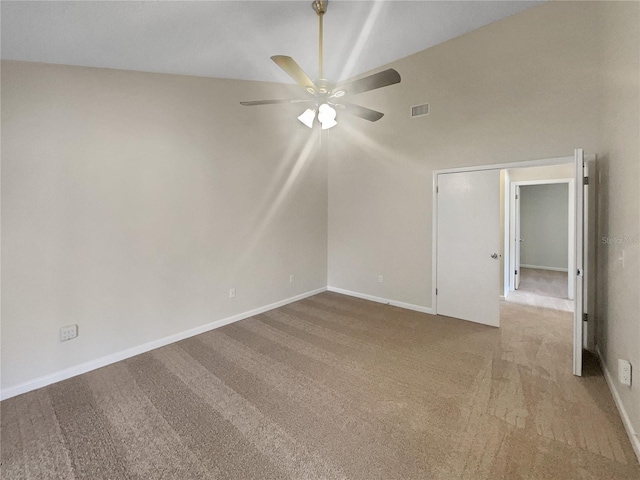 spare room featuring a ceiling fan, visible vents, carpet floors, baseboards, and lofted ceiling