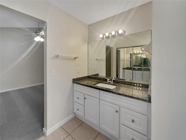 bathroom with baseboards, vanity, tile patterned floors, a textured ceiling, and a ceiling fan