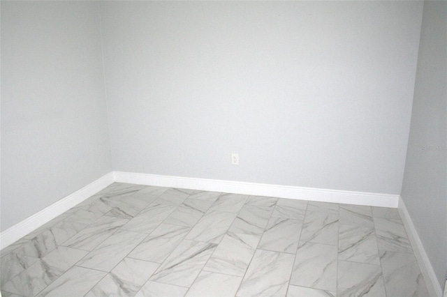 spare room featuring baseboards and marble finish floor