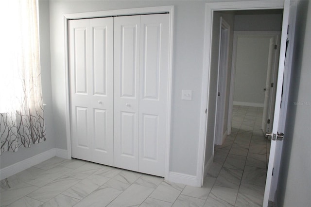 unfurnished bedroom featuring a closet, baseboards, and marble finish floor