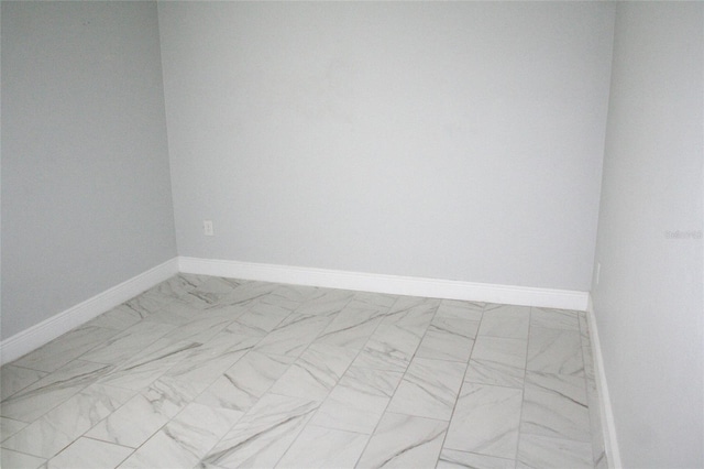 spare room with marble finish floor and baseboards