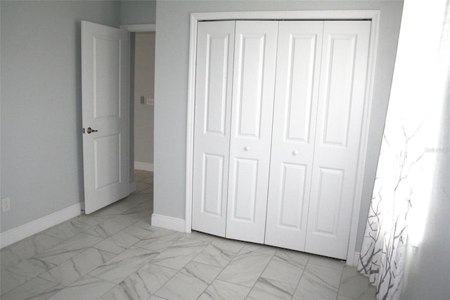 unfurnished bedroom featuring a closet, marble finish floor, and baseboards