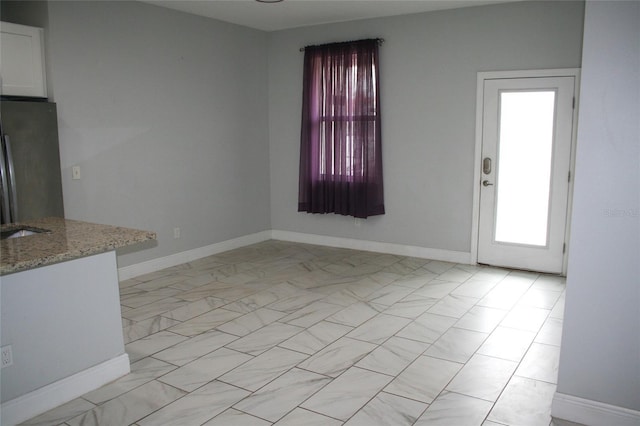 unfurnished dining area featuring baseboards and marble finish floor