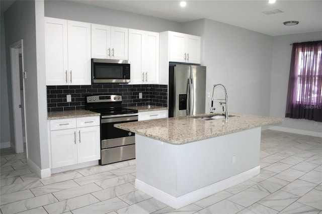 kitchen featuring light stone countertops, stainless steel appliances, sink, a center island with sink, and white cabinetry