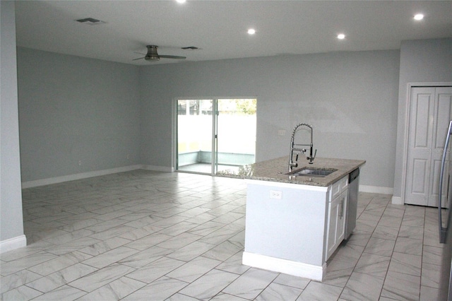 kitchen featuring white cabinets, sink, stainless steel dishwasher, light stone countertops, and an island with sink