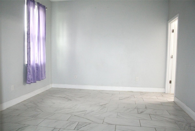 spare room featuring marble finish floor and baseboards