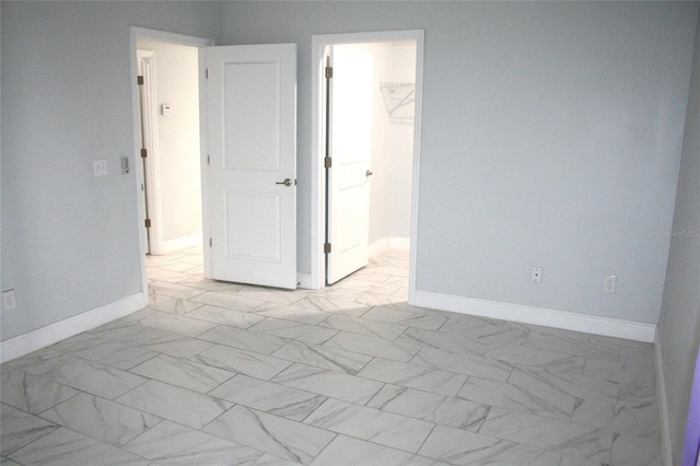 unfurnished bedroom with baseboards and marble finish floor