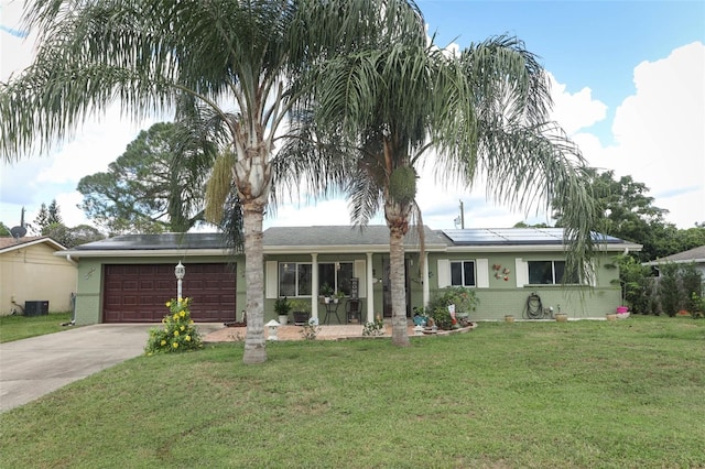 ranch-style home with a garage, a front yard, and solar panels