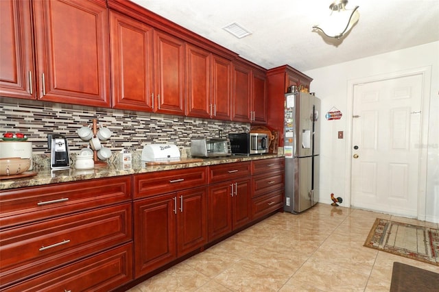 kitchen featuring stone counters, tasteful backsplash, a textured ceiling, appliances with stainless steel finishes, and light tile patterned flooring