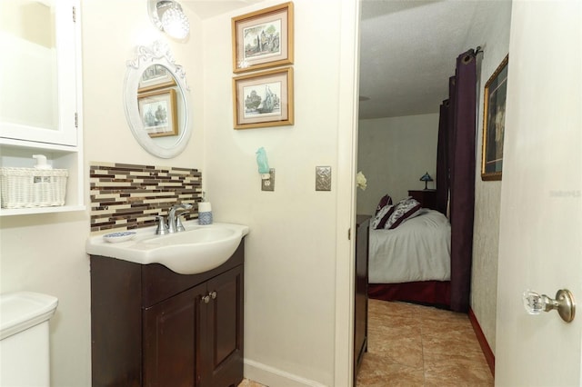 bathroom featuring vanity, toilet, a textured ceiling, and tasteful backsplash