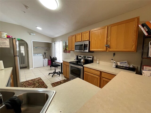 kitchen with stainless steel appliances, sink, washer / dryer, vaulted ceiling, and light tile patterned flooring