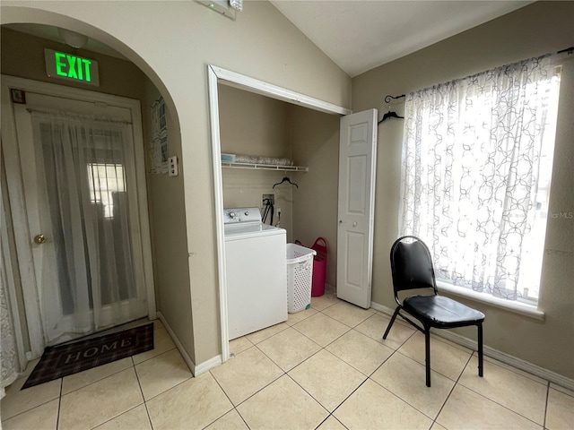 laundry area featuring light tile patterned floors, arched walkways, laundry area, baseboards, and washer / clothes dryer