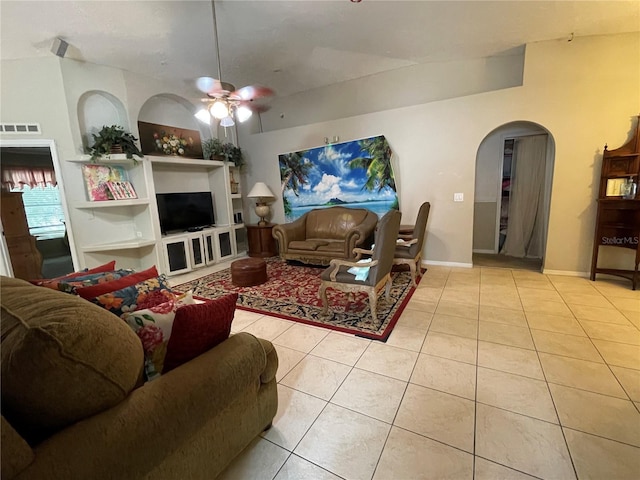 tiled living area with arched walkways, ceiling fan, visible vents, built in features, and baseboards