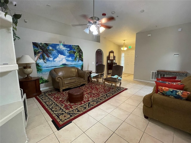 living room featuring a ceiling fan, arched walkways, light tile patterned flooring, and visible vents