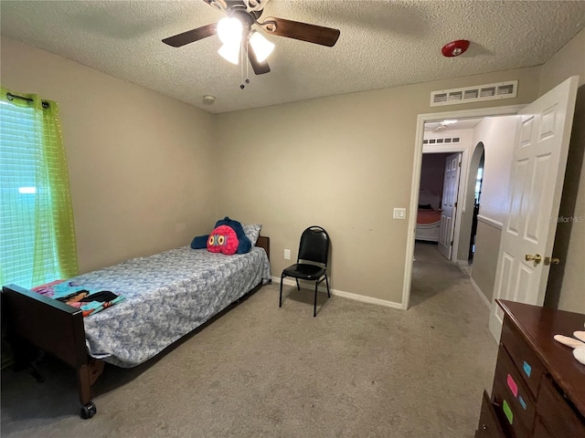 carpeted bedroom featuring visible vents, arched walkways, a ceiling fan, baseboards, and a textured ceiling