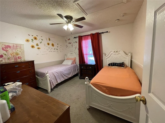 carpeted bedroom featuring attic access, a textured ceiling, and a ceiling fan