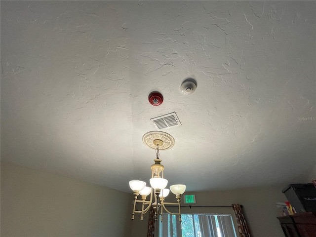 interior details with visible vents, a chandelier, and a textured ceiling