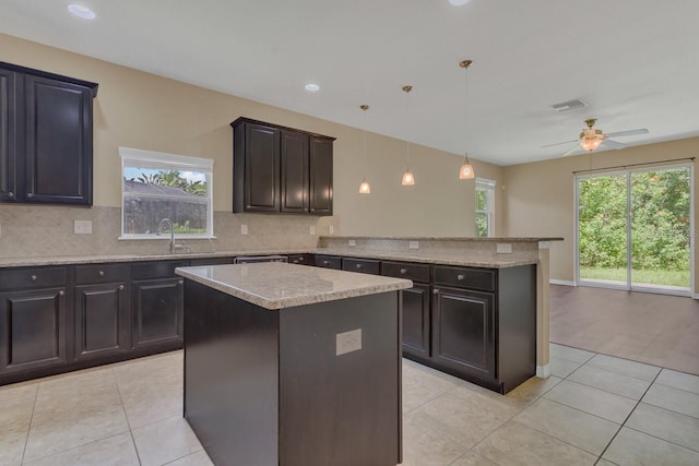 kitchen featuring hanging light fixtures, a center island, tasteful backsplash, and ceiling fan