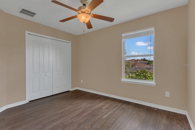 unfurnished bedroom featuring dark wood-type flooring, baseboards, visible vents, and a closet