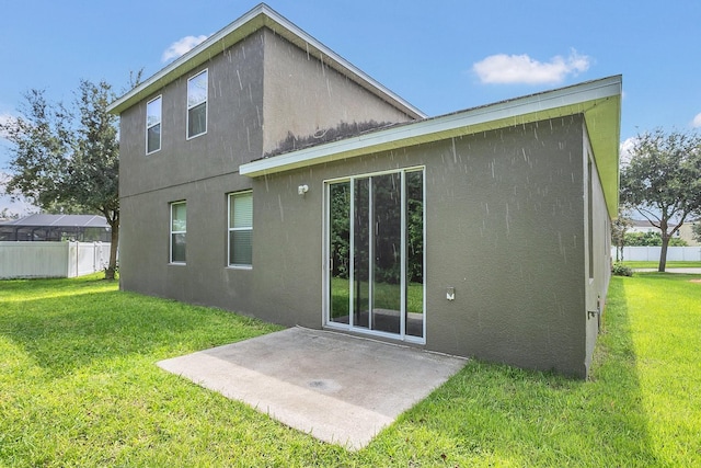 back of property with a yard, a patio, stucco siding, and fence