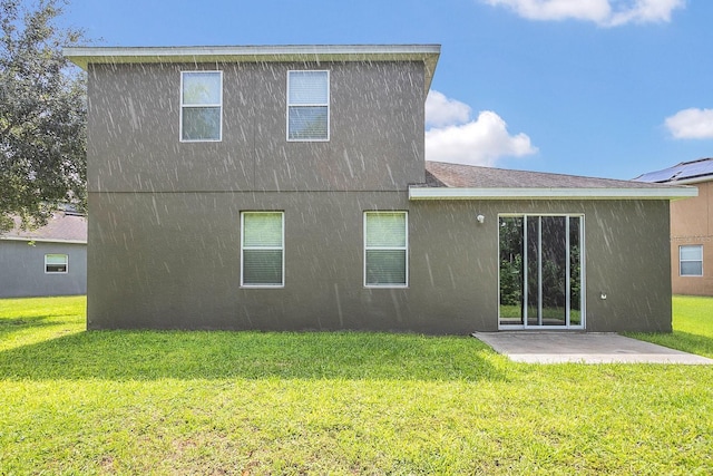 rear view of house with a yard, a patio area, and stucco siding